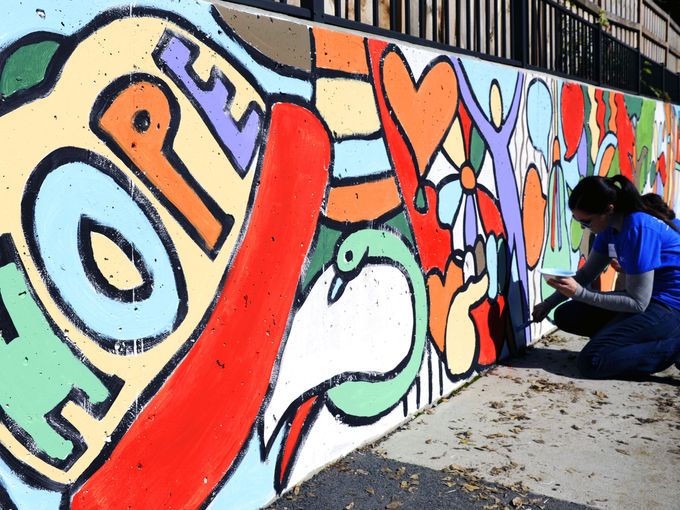 Amanda Stencel of HCA paints a large mural on the playground at Safe Haven Family Shelter on Oct. 23, 2014